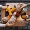 Zapakowane do kartonu produkty spożywcze – butelki z sokiem, słoiki z oliwkami i suche produkty