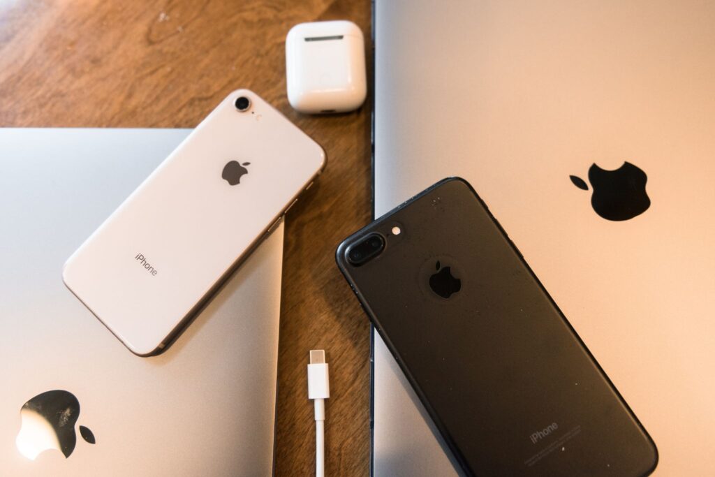 Sprzęt elektroniczny apple - dwa iphone;y - biały i czarny leżace na komputerach mac book