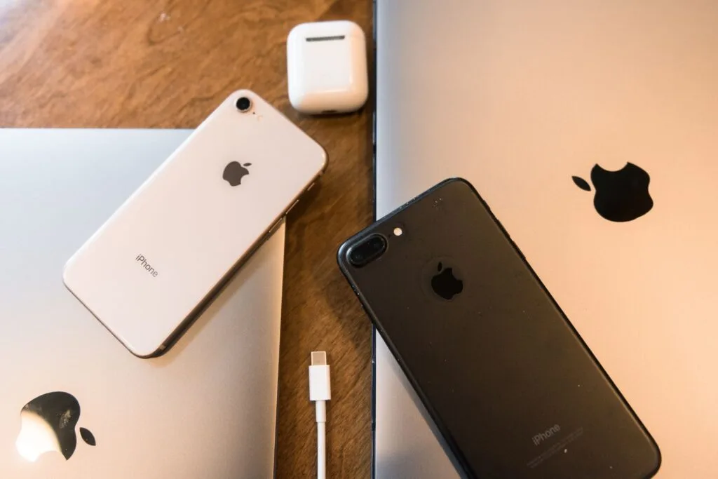 Sprzęt elektroniczny apple - dwa iphone;y - biały i czarny leżace na komputerach mac book