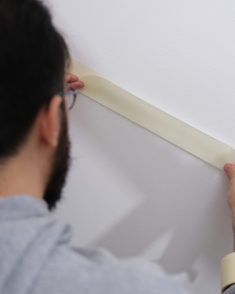 Hurtownia taśmy malarskiej mężczyzna przyklejający taśmę malarską do ściany