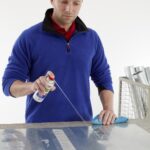 zmywacz w sprayu tesa do usuwania resztek kleju ujęcie na mężczyznę rozpylającego zmywacz w sprayu na oklejoną powierzchnię