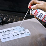 Zmywacz w sprayu do kleju z taśm mężczyzna rozpylający zmywacz w sprawyu na powierzchnię