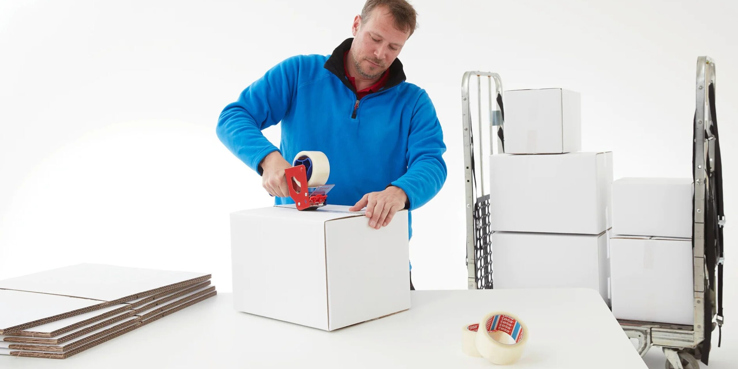 taśmy pakowe – jaka wybrac mezczyzna zaklejajacy bialy karton przezroczysta tasma nawinieta na dyspenser