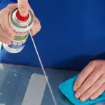 a man spraying adhesive remover onto a surface
