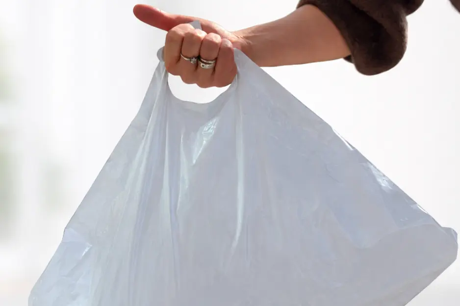 Hand, die einen gefüllten Versandbeutel am Eckgriff hält
